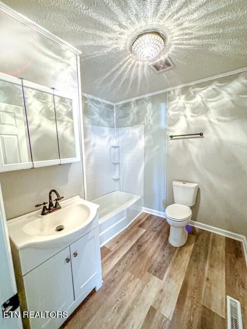 full bathroom with a textured ceiling, hardwood / wood-style floors, toilet, vanity, and bathing tub / shower combination