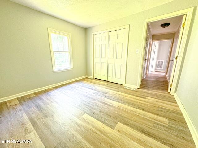 unfurnished bedroom featuring a closet and hardwood / wood-style floors