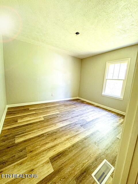 unfurnished room featuring a textured ceiling and hardwood / wood-style floors