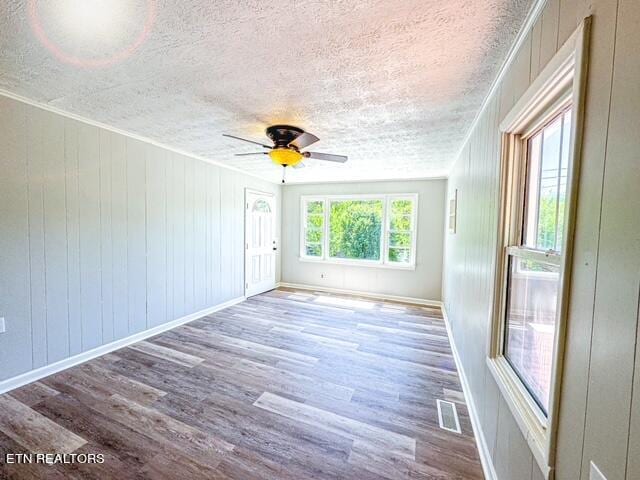 unfurnished room with ceiling fan, hardwood / wood-style flooring, and a textured ceiling