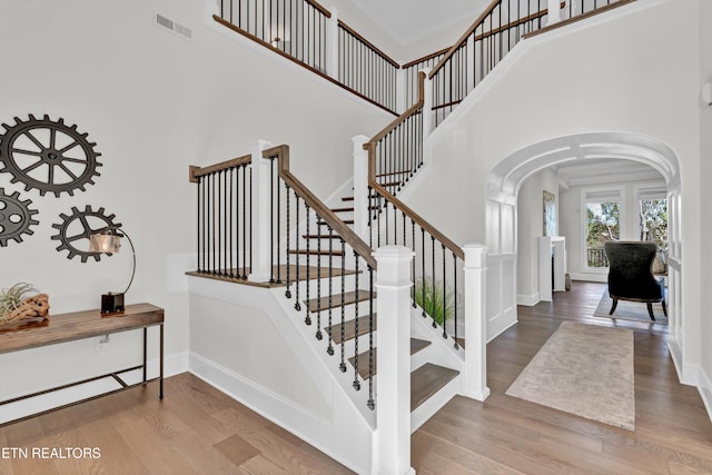 staircase with hardwood / wood-style floors and a towering ceiling