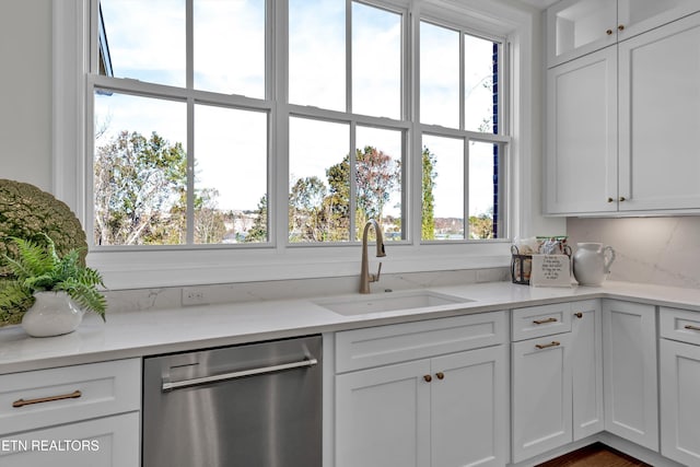 kitchen featuring light stone counters, sink, white cabinets, and stainless steel dishwasher