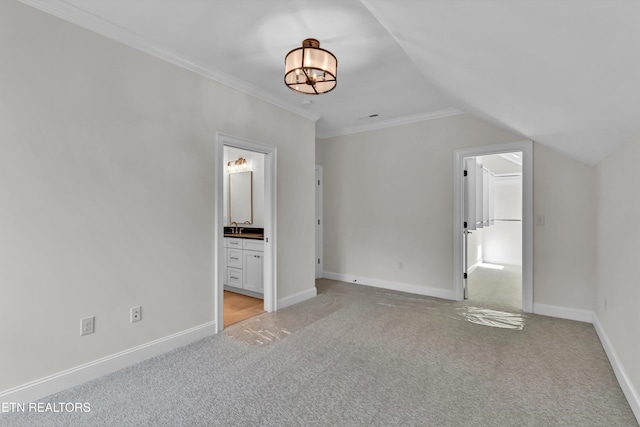 unfurnished bedroom featuring lofted ceiling, sink, ornamental molding, light colored carpet, and ensuite bathroom