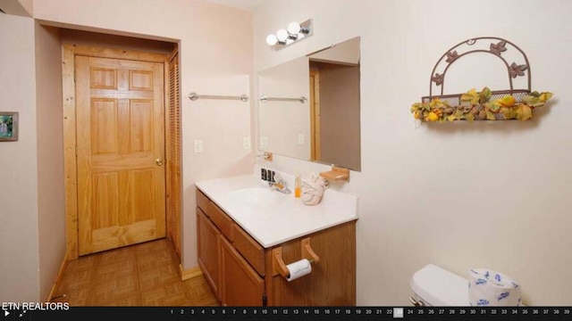 bathroom featuring vanity, parquet floors, and toilet