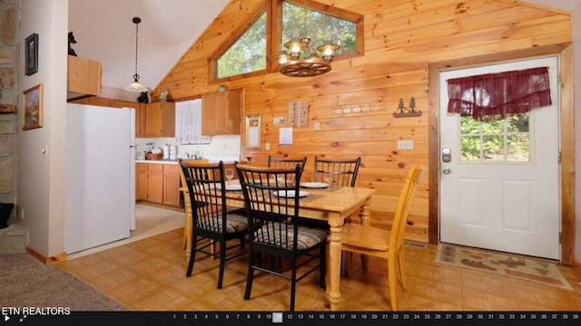 dining area featuring high vaulted ceiling, wood walls, and light parquet floors