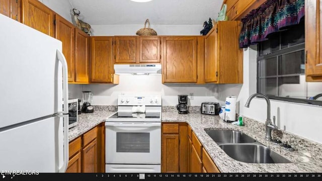 kitchen featuring white appliances, light stone countertops, and sink