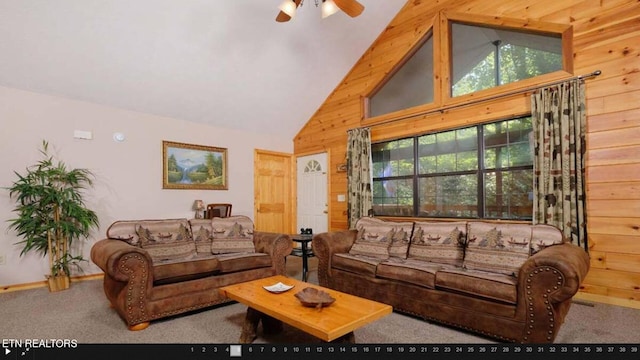 carpeted living room with a healthy amount of sunlight, wood walls, high vaulted ceiling, and ceiling fan