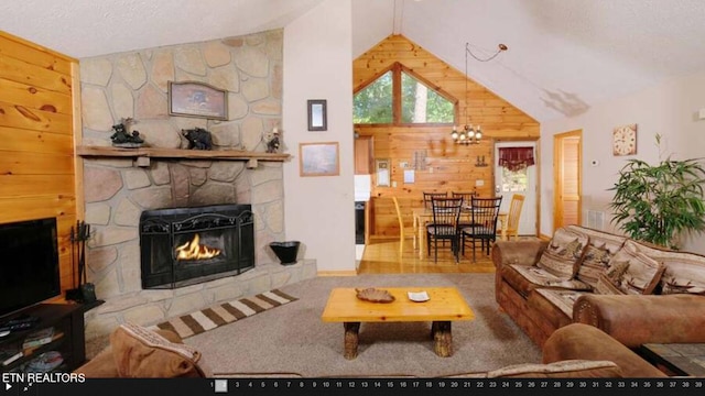 living room featuring wood walls, carpet floors, an inviting chandelier, a stone fireplace, and lofted ceiling