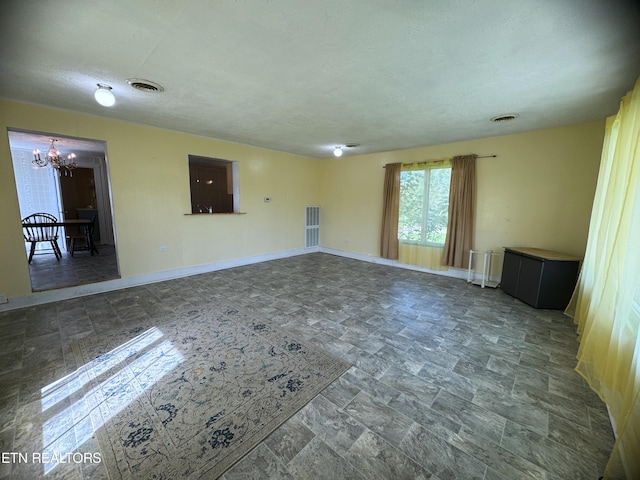 tiled spare room featuring an inviting chandelier and a textured ceiling