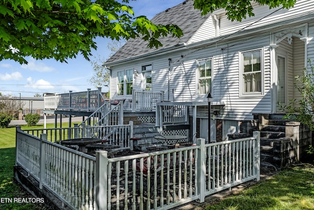 back of house featuring a deck and a lawn