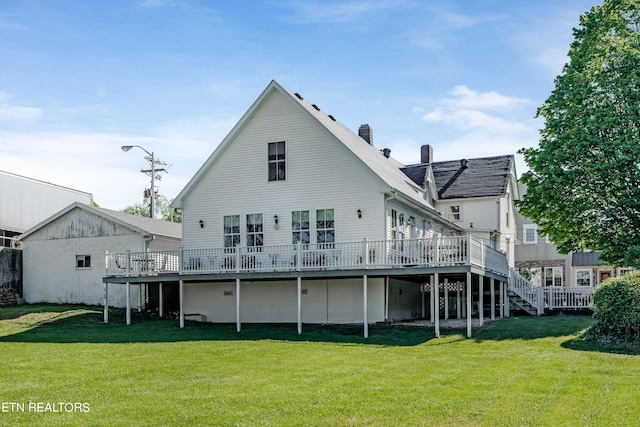 rear view of property featuring a wooden deck and a lawn