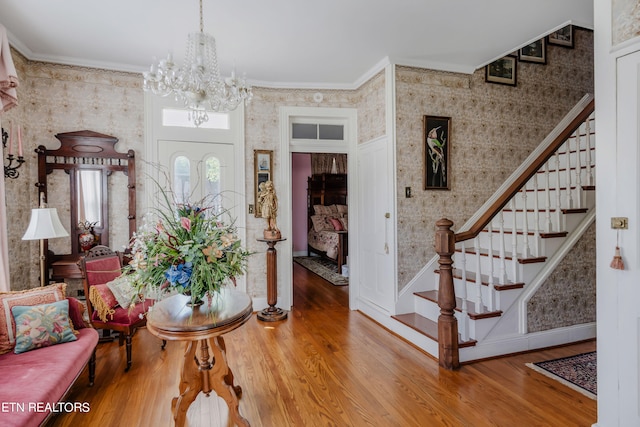 foyer featuring wood-type flooring, a chandelier, and ornamental molding