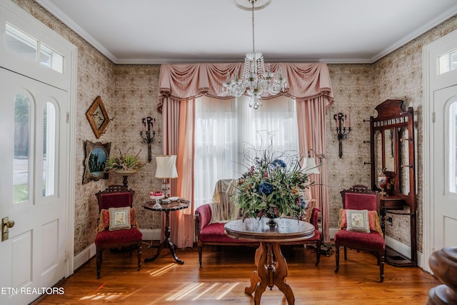 sitting room featuring hardwood / wood-style flooring, plenty of natural light, ornamental molding, and a chandelier