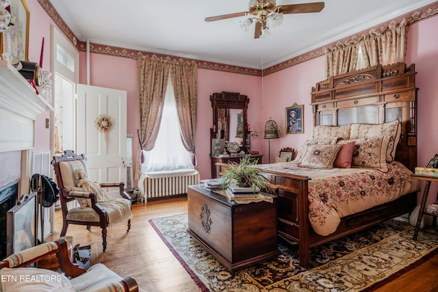 bedroom featuring hardwood / wood-style floors, ceiling fan, and radiator heating unit