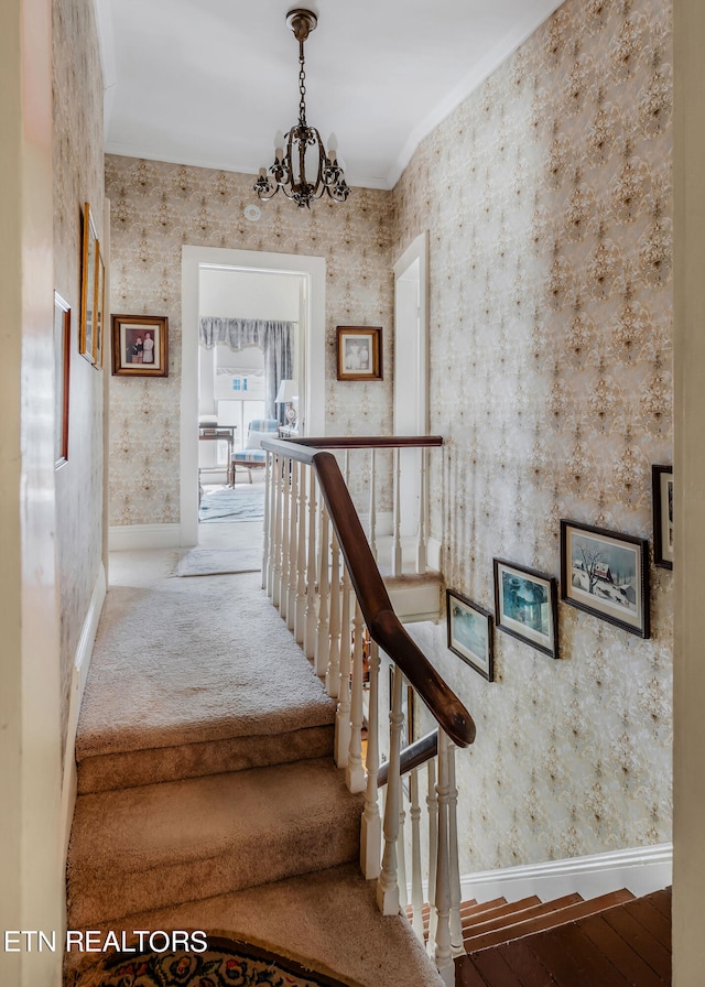 stairway featuring hardwood / wood-style floors, a notable chandelier, and crown molding