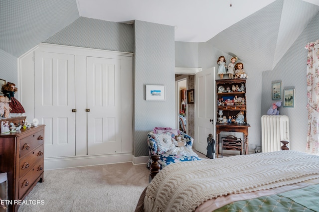 carpeted bedroom with vaulted ceiling, a closet, and radiator