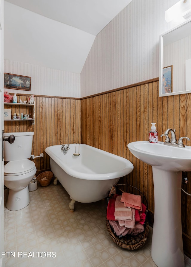 bathroom with a washtub, tile floors, toilet, and wooden walls