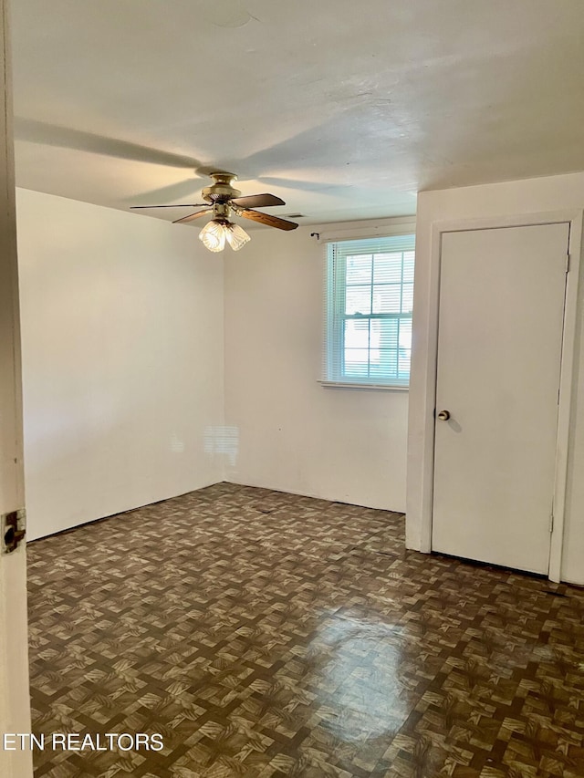 spare room featuring dark parquet floors and ceiling fan