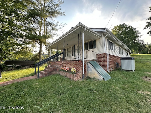 view of side of property featuring central AC unit, a porch, and a lawn