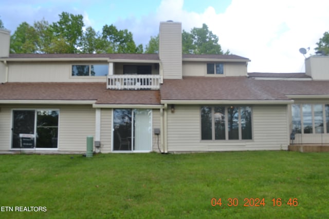 rear view of house featuring a balcony and a yard