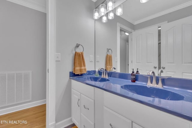 bathroom with wood-type flooring, oversized vanity, crown molding, and double sink