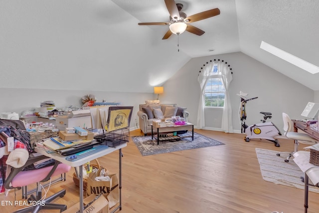 interior space featuring light hardwood / wood-style flooring, lofted ceiling with skylight, ceiling fan, and a textured ceiling