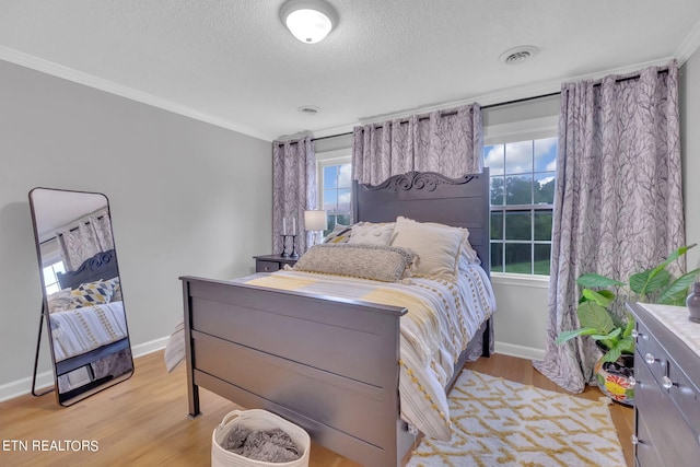 bedroom with light hardwood / wood-style flooring, crown molding, and a textured ceiling