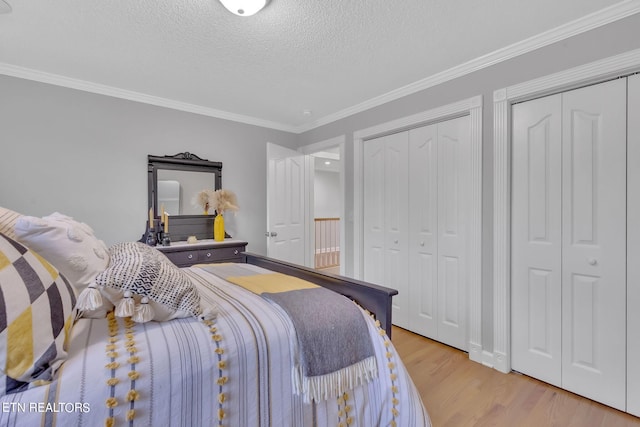 bedroom with crown molding, multiple closets, a textured ceiling, and light wood-type flooring