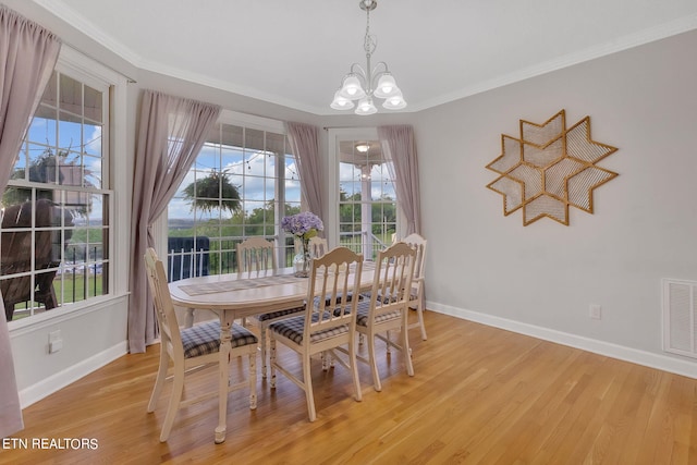 dining area featuring ornamental molding, a notable chandelier, and light wood-type flooring