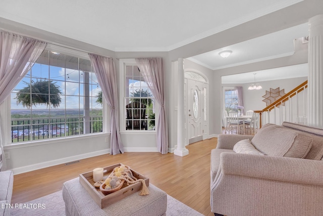 living room with wood-type flooring, a healthy amount of sunlight, a chandelier, and crown molding