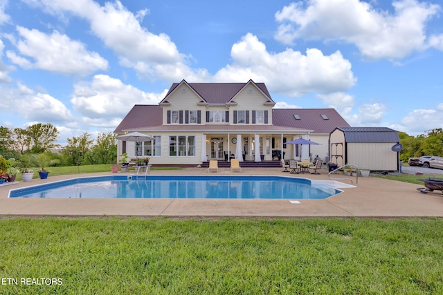 view of pool with a patio area, an outdoor structure, and a lawn