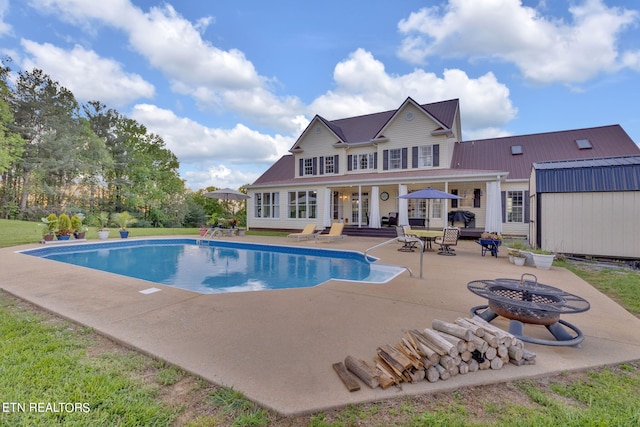 view of swimming pool with a fire pit, an outdoor structure, and a patio area