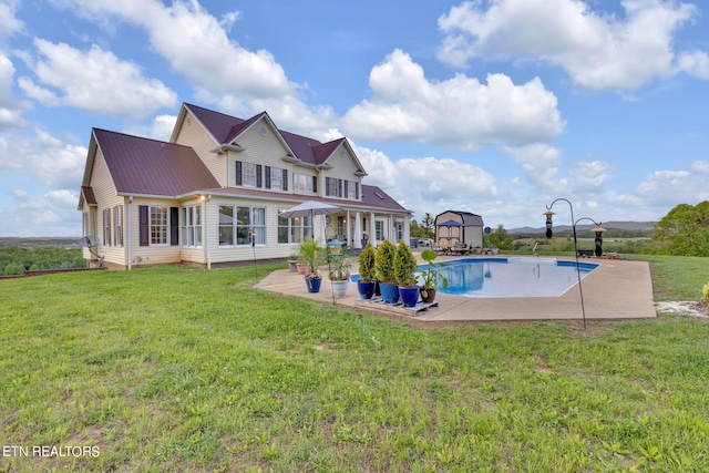 view of pool with a patio area, an outdoor structure, and a lawn