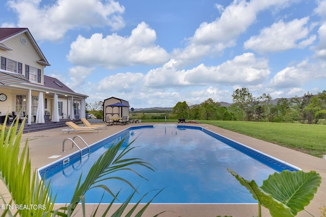 view of pool with a patio, a yard, and a shed