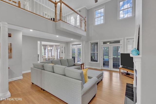 living room with light hardwood / wood-style floors, french doors, and a towering ceiling