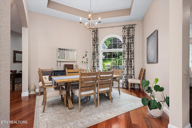 dining room featuring hardwood / wood-style floors, a tray ceiling, and a notable chandelier