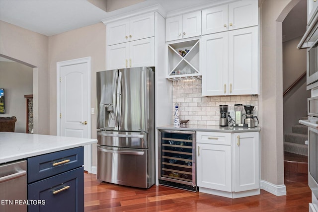 kitchen featuring stainless steel appliances, dark hardwood / wood-style floors, blue cabinetry, wine cooler, and white cabinets