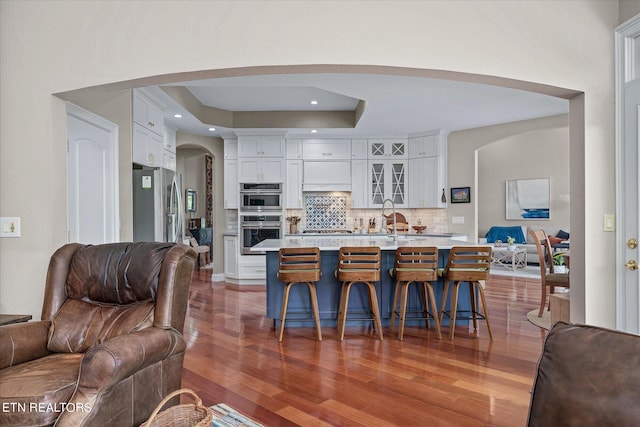 kitchen featuring white cabinetry, appliances with stainless steel finishes, a raised ceiling, backsplash, and a breakfast bar