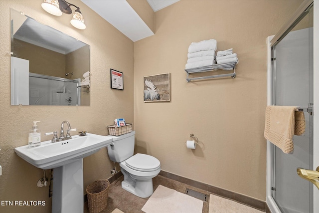 bathroom with a shower with shower door, sink, tile patterned floors, and toilet