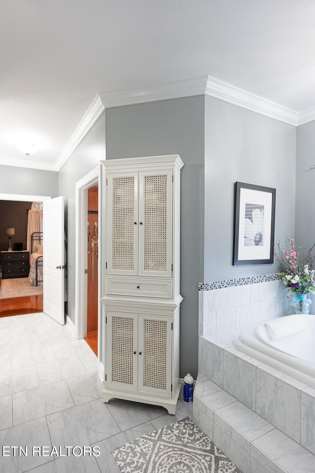 bathroom with ornamental molding and tiled bath