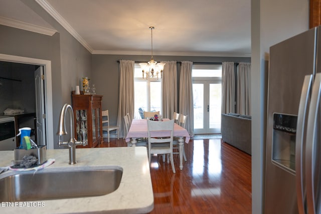 dining area with sink, french doors, dark wood-type flooring, a notable chandelier, and ornamental molding