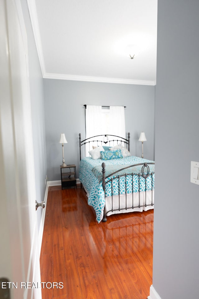 bedroom featuring crown molding and wood-type flooring