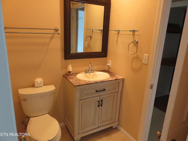 half bath with baseboards, vanity, and toilet