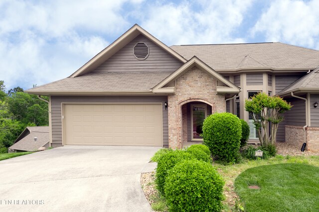 view of front of house with a garage, brick siding, driveway, and roof with shingles