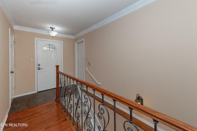 entryway with ornamental molding, wood finished floors, and baseboards