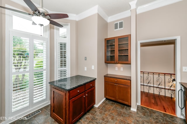 kitchen with dark stone counters, ornamental molding, glass insert cabinets, and visible vents