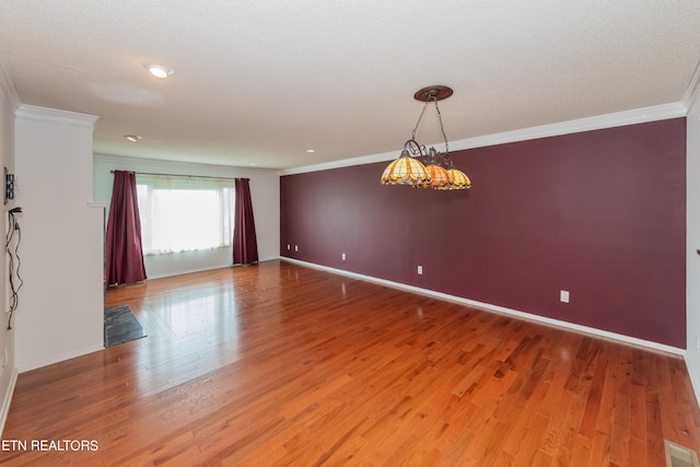 empty room featuring ornamental molding, visible vents, light wood-style flooring, and baseboards