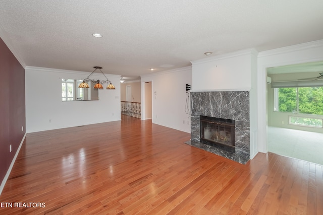 unfurnished living room with crown molding, a textured ceiling, hardwood / wood-style floors, and a high end fireplace