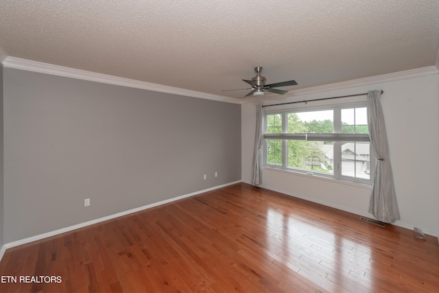 spare room with a textured ceiling, ornamental molding, wood finished floors, and visible vents