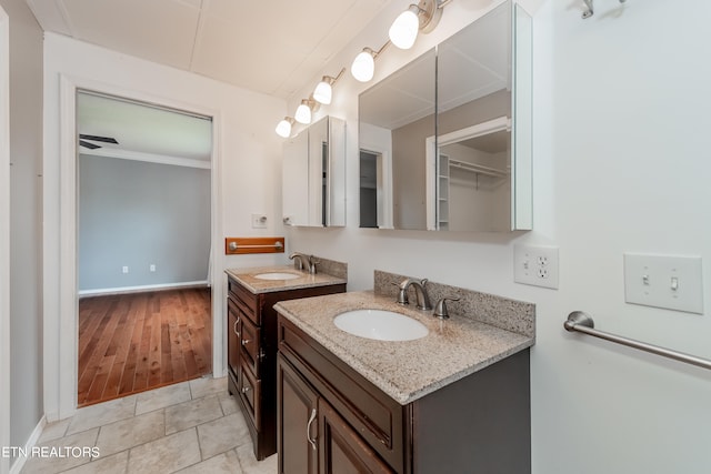 bathroom with tile patterned flooring, ornamental molding, two vanities, and a sink